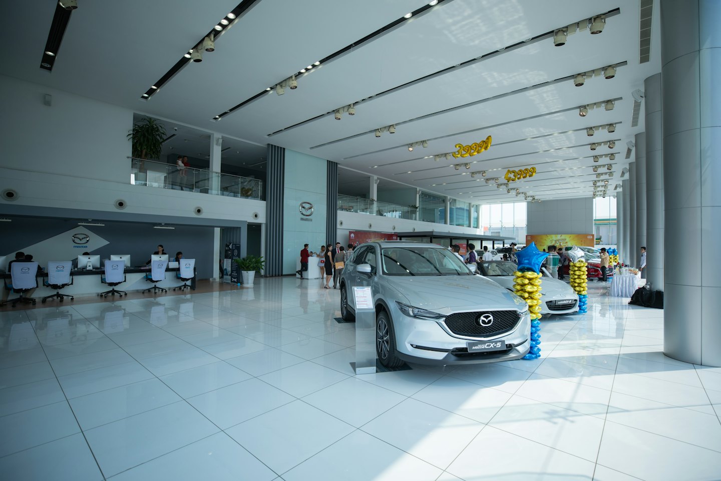 New silver Mazda cars displayed in a bright dealership showroom.