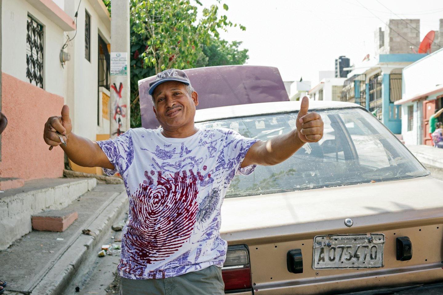 Man holding car keys gives thumbs up by his vehicle.